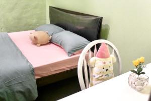 uma cama com um ursinho de peluche, uma almofada e uma mesa em Relish The Moment em Malaca