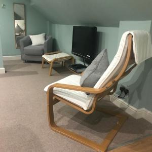 uma sala de estar com uma cadeira e uma televisão em Somersall Park Studio em Chesterfield