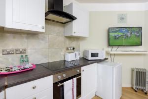 een keuken met witte kasten en een tv aan de muur bij Gloucester Gardens in Londen