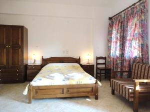 1 dormitorio con cama, silla y cortinas en Yellow Stella Studios, en Skopelos Town