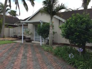 a house with a palm tree and a brick driveway at Porpoise Lodge in Richards Bay