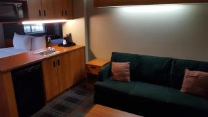 a living room with a green couch and a kitchen at Microtel Inn & Suites by Wyndham Bozeman in Bozeman