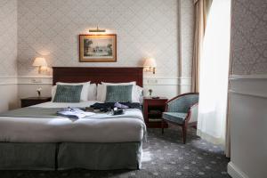 a hotel room with a bed, chair, and nightstand at Emperador in Madrid