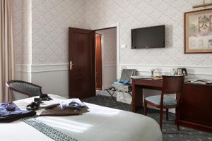 Habitación de hotel con cama, escritorio y TV. en Emperador, en Madrid
