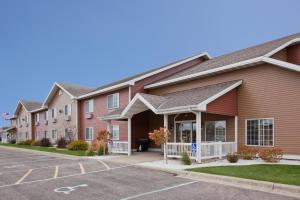 a row of apartment buildings with a parking lot at Paynesville Inn & Suites in Paynesville