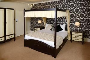 a bedroom with a canopy bed with black and white wallpaper at Stags Head Hotel in Bowness-on-Windermere