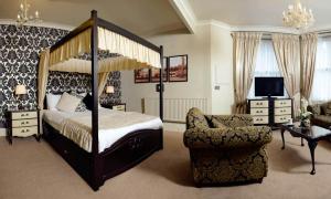 a bedroom with a canopy bed and a chair at Stags Head Hotel in Bowness-on-Windermere