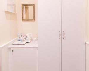 a white kitchen with white cabinets and a sink at Unitas Hotel in Prague