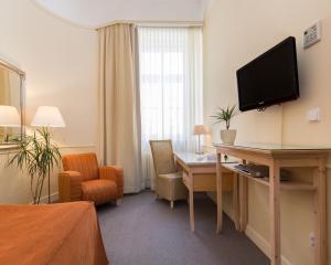 Habitación de hotel con escritorio y TV en la pared en Unitas Hotel, en Praga