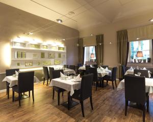 jadalnia z białymi stołami i czarnymi krzesłami w obiekcie Unitas Hotel w Pradze