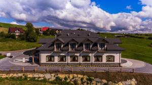 Una casa grande con techo negro en una calle. en Pensjonat Perła Pienin, en Grywałd