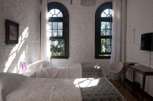 a bedroom with a bed and a desk and two windows at Santoral Restaurante y Posada Pet Friendly in Atlántida