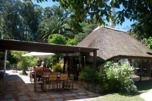 a group of people sitting at a restaurant with a thatch roof at Santoral Restaurante y Posada Pet Friendly in Atlántida