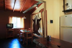 Un comedor con una mesa y un refrigerador. en Cabañas Atardeceres, en Capilla del Monte