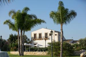 a white house with palm trees in front of it at Casal Sikelio in Cassibile