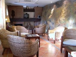 a room with wicker chairs and tables and a fireplace at La Higuera in Güéjar-Sierra