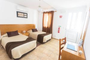 a room with two beds and a desk with a laptop at Apartamentos Oliveira in Madalena