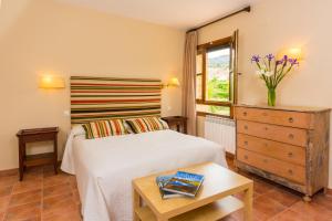 a bedroom with a bed and a dresser and a window at Font del Pas in Beceite