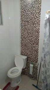 a bathroom with a toilet and a tiled wall at Apartamento Praia da Costa in Vila Velha
