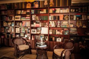 une bibliothèque avec deux chaises, une table et des livres dans l'établissement Casa de Khasia, à Zugdidi