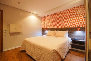 um quarto com uma cama e uma parede laranja em Hotel Biz em São Paulo