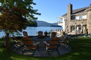 a patio with chairs and a table next to a lake at Lake George Boathouse Waterfront Lodging in Bolton Landing