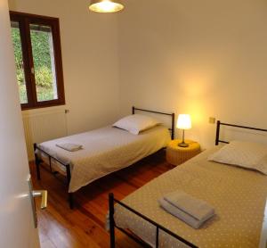1 dormitorio con 2 camas, ventana y lámpara en Le Clos Gentiane, en Saint-Étienne