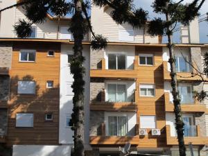 un edificio con árboles delante de él en Temporada Gramado e Canela - Apartamento Centro Campos de Canella, en Canela