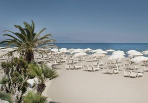 plaży z leżakami, parasolami i palmami w obiekcie B&B Volì Club w mieście Siderno Marina