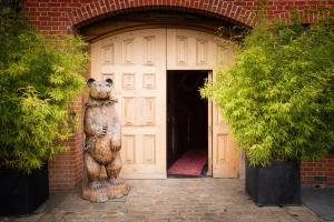 Una statua di un orso che si trova davanti a una porta di Crazy Bear Beaconsfield a Beaconsfield