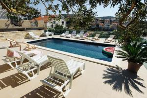 ein Schwimmbecken mit vielen Stühlen drumherum in der Unterkunft Apartments Martina in Primošten