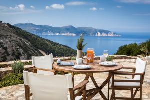 a wooden table and chairs with a view of the ocean at Myrtos View Apartments in Anomeriá