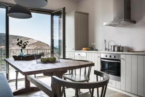 a kitchen with a wooden table with chairs and a view at Myrtos View Apartments in Anomeriá