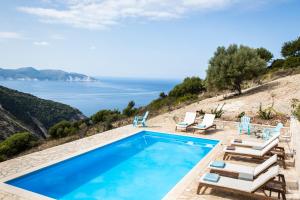 a pool with chairs and a view of the ocean at Myrtos View Apartments in Anomeriá