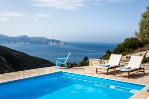 a pool with two chairs and a view of the ocean at Myrtos View Apartments in Anomeriá