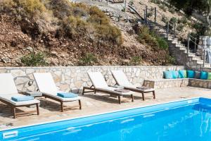 a row of lounge chairs next to a swimming pool at Myrtos View Apartments in Anomeriá