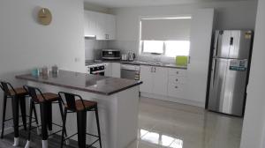 a kitchen with a counter with stools and a refrigerator at Dreamcatcher@Bicheno in Bicheno