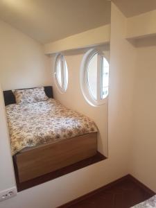 een kleine slaapkamer met een bed en 2 ramen bij Apolon in Novi Sad