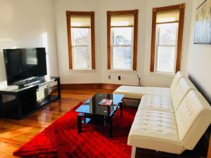 a living room with a white couch and a tv at Boston Lodge and Suites in Boston