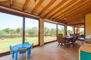 a living room with tables and chairs and large windows at Villa Santa Eulalia in Can Picafort