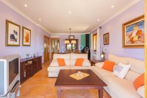 sala de estar con sofá blanco y TV en Villa Santa Eulalia, en Can Picafort