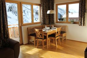 comedor con mesa, sillas y ventanas en Appartements Aurora, en Damüls