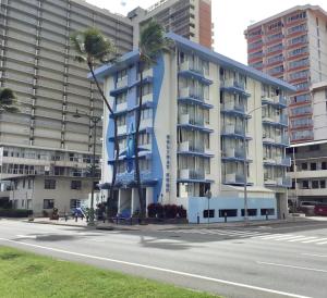 un bâtiment avec des palmiers en face d'une rue dans l'établissement Holiday Surf Hotel (with full kitchen), à Honolulu