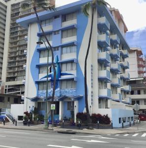 um edifício azul com palmeiras em frente em Holiday Surf Hotel (with full kitchen) em Honolulu