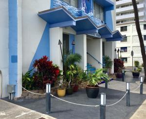 a blue and white building with plants in front of it at Holiday Surf Hotel (with full kitchen) in Honolulu
