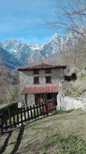 a stone house with a fence and mountains in the background at Casa La Ribera in Lon