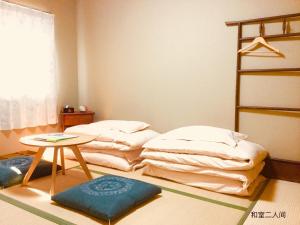a room with two beds and a table in it at Guesthouse Kyoto Arashiyama in Kyoto