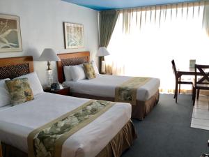 um quarto de hotel com duas camas e uma mesa em Holiday Surf Hotel (with full kitchen) em Honolulu