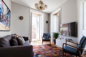 a living room with a couch and a tv at Alfama Sophisticate Flat With Balconies 2Bedrs 2Baths & AC in 19th Century Building Historic Center in Lisbon