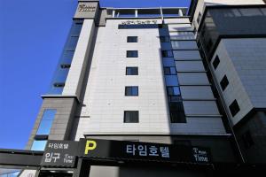 un grand bâtiment avec un panneau devant lui dans l'établissement Time Hotel, à Yangsan